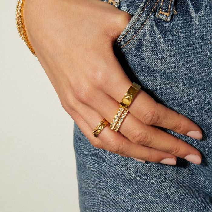 Model. Hand wearing gold rings with a denim background