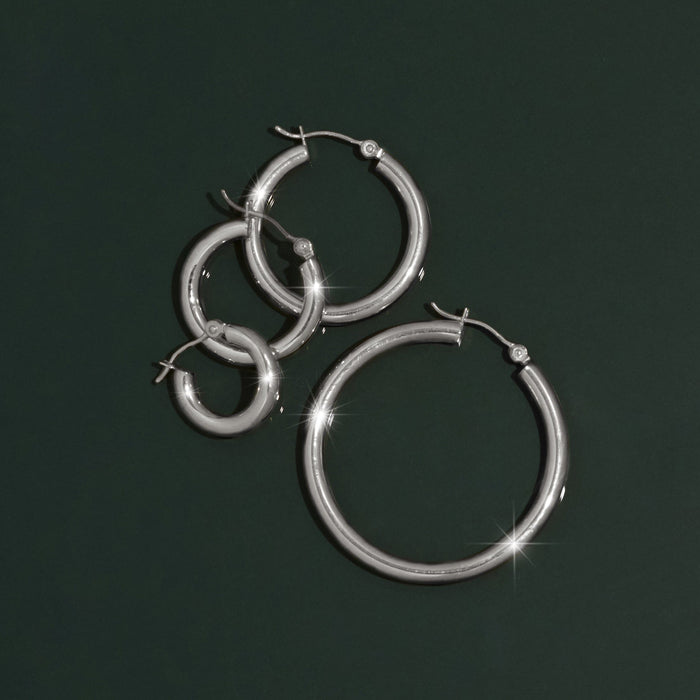 Model.  various silver hoop earrings on a green background