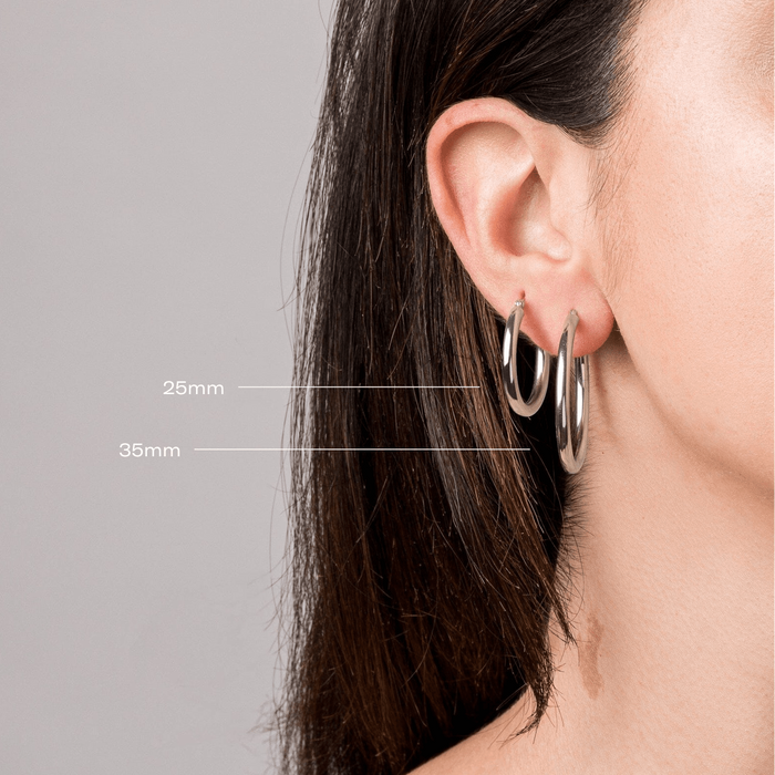 Model two silver hoop earrings in a woman's ear close up