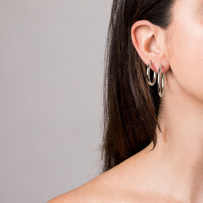 two silver hoop earrings in a woman's ear close up