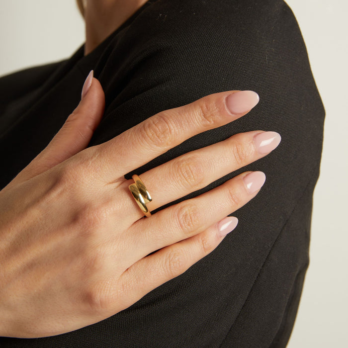 Model Hand wearing a gold ring with a plain background
