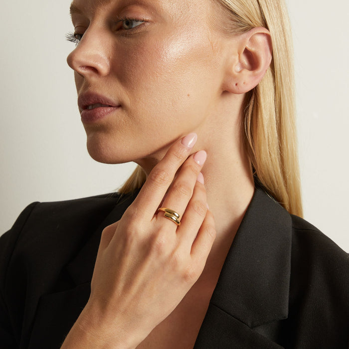 Model Close-up of a woman wearing a gold ring on her finger, with a neutral background.