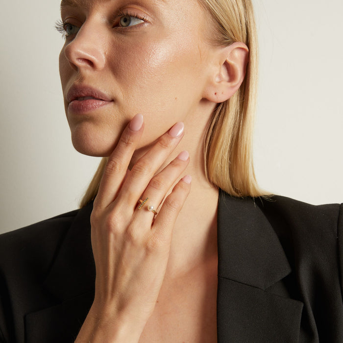 Model Woman wearing a gold ring on her finger, touching her neck against a neutral background