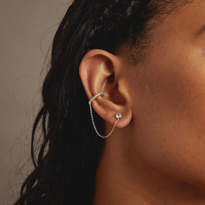 Model Close-up of an ear wearing a silver earring with a chain detail.