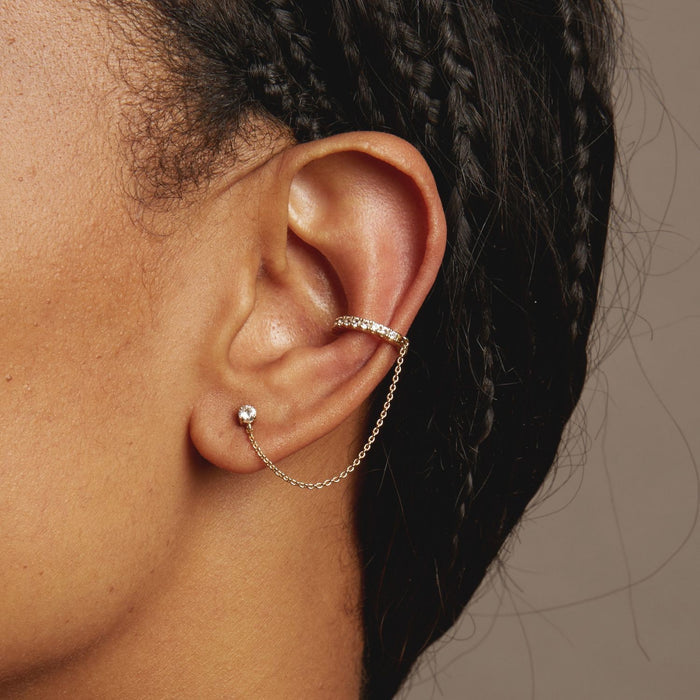 Model Close-up of an ear wearing gold hoop earrings with a blurred background