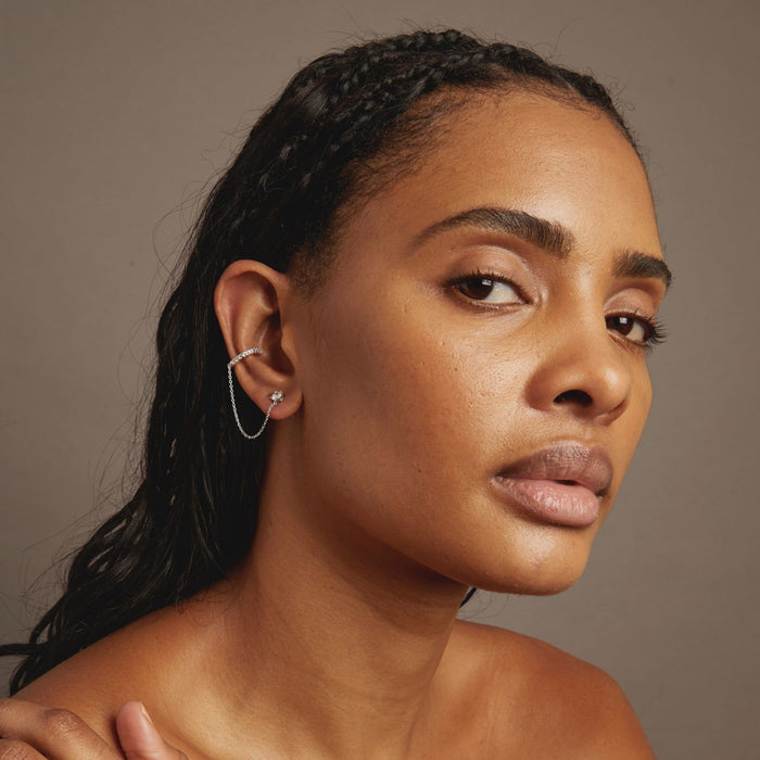 Model Woman with braided hair wearing a silver earring against a neutral background