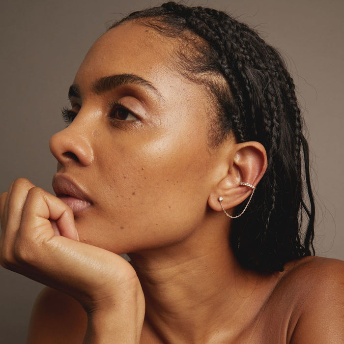 Model Woman with braided hair wearing a silver earring against a neutral background