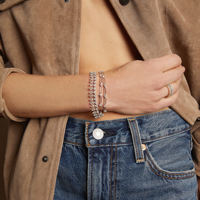 Model. Person wearing a brown jacket and blue jeans with visible jewelry.