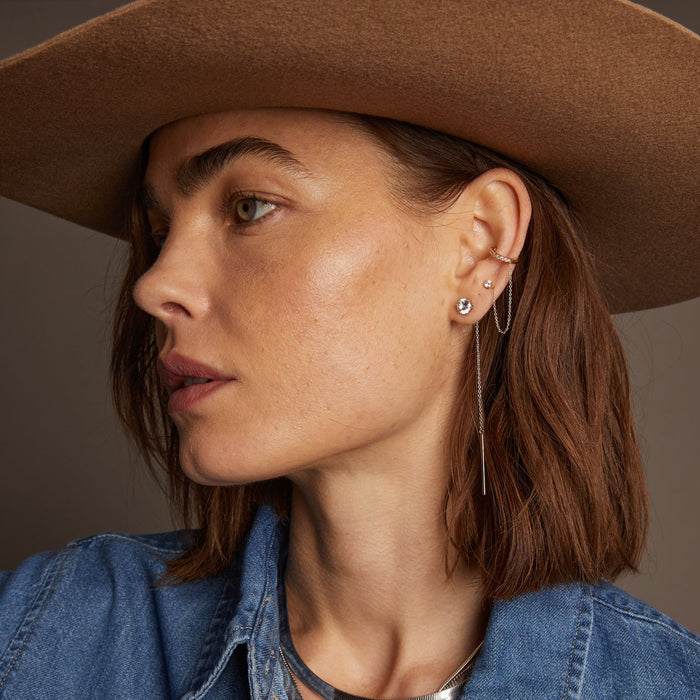 Model. Side profile of woman wearing hat with chain earrings