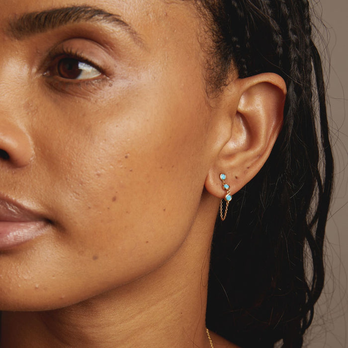 Model Close-up of a woman's ear with turquoise earrings against a neutral background