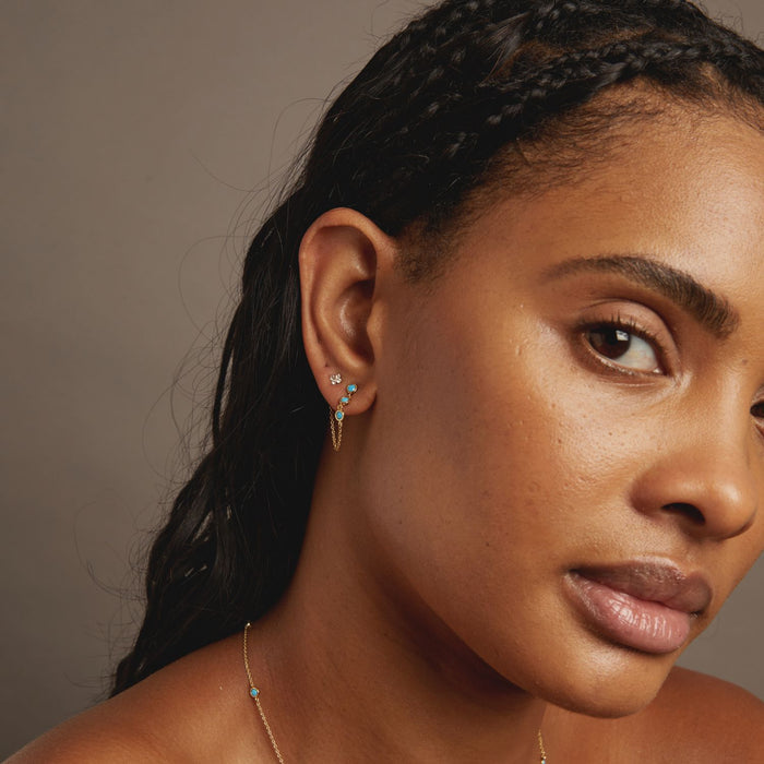 Model Close-up of a woman's face with earrings and necklace against a neutral background
