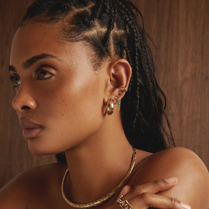 Model Woman wearing gold jewelry with a neutral background