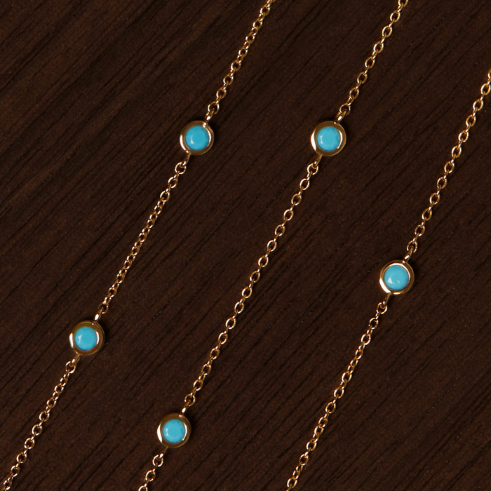 Model Gold necklaces with turquoise stones on a wooden surface