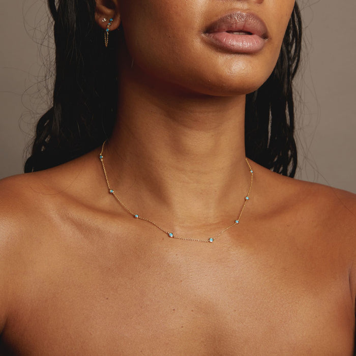 Close-up of a woman wearing a delicate necklace against a neutral background