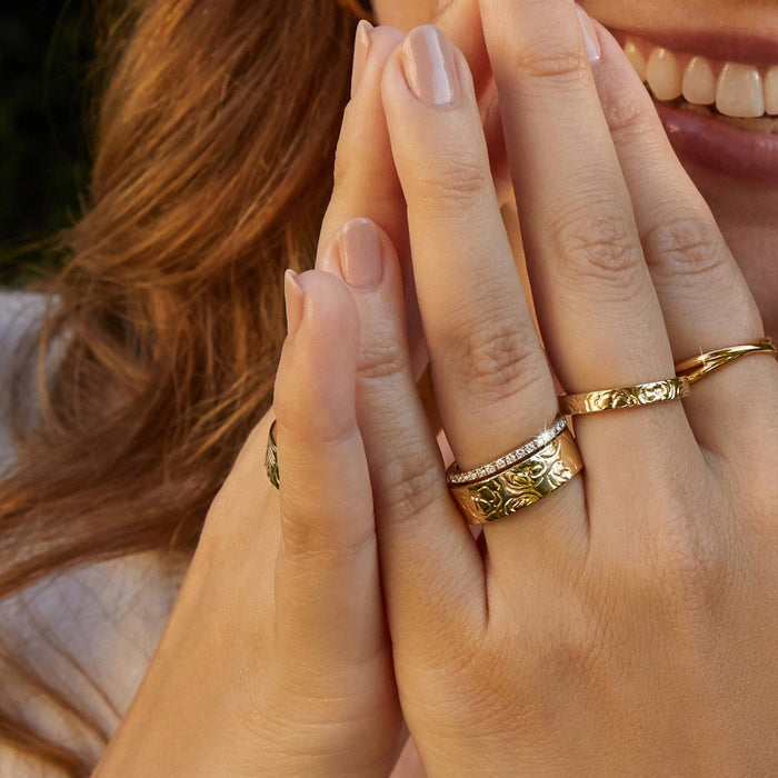 Lifestyle Model Close-up of a woman clasping her hands near her face, wearing a stack of gold rings