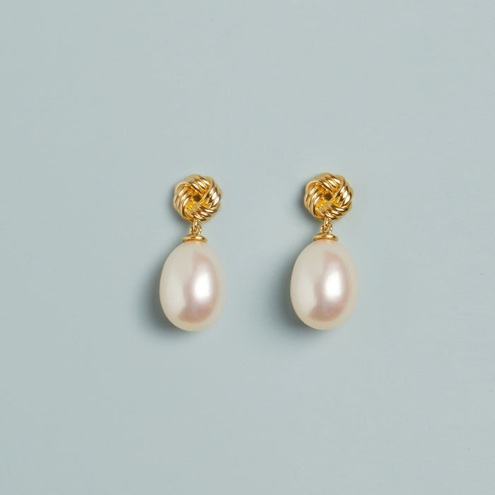 Model. Pearl earrings on blue background.