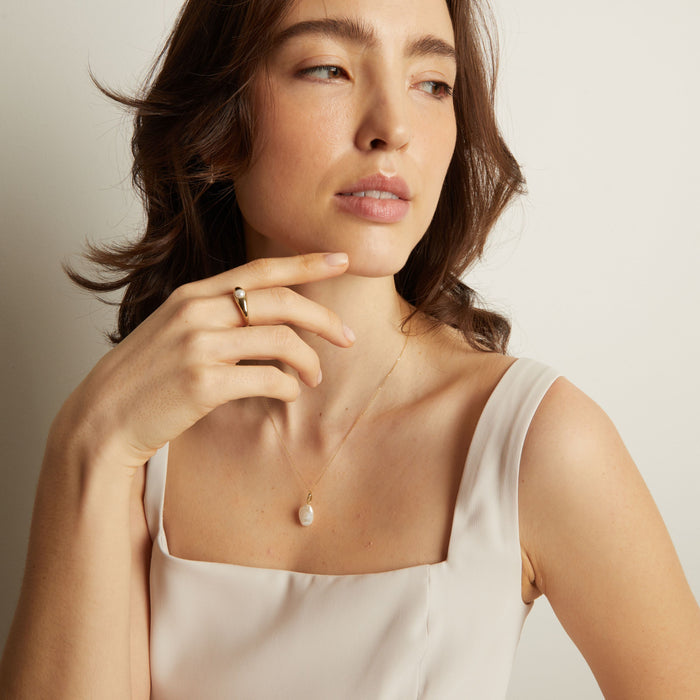 Model Woman wearing a delicate necklace with a minimal background
