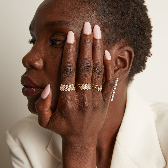 Woman wearing various rings with white sapphire gemstones.