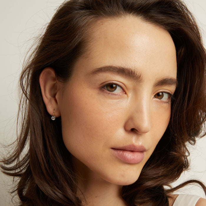Close-up of a woman with wavy brown hair against a neutral background