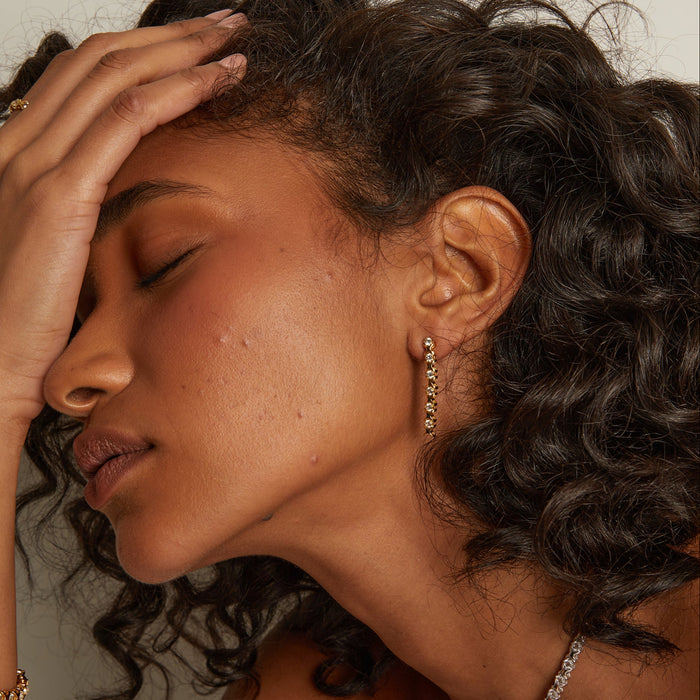 Model. Close-up of a woman with curly hair wearing earrings, with a neutral background