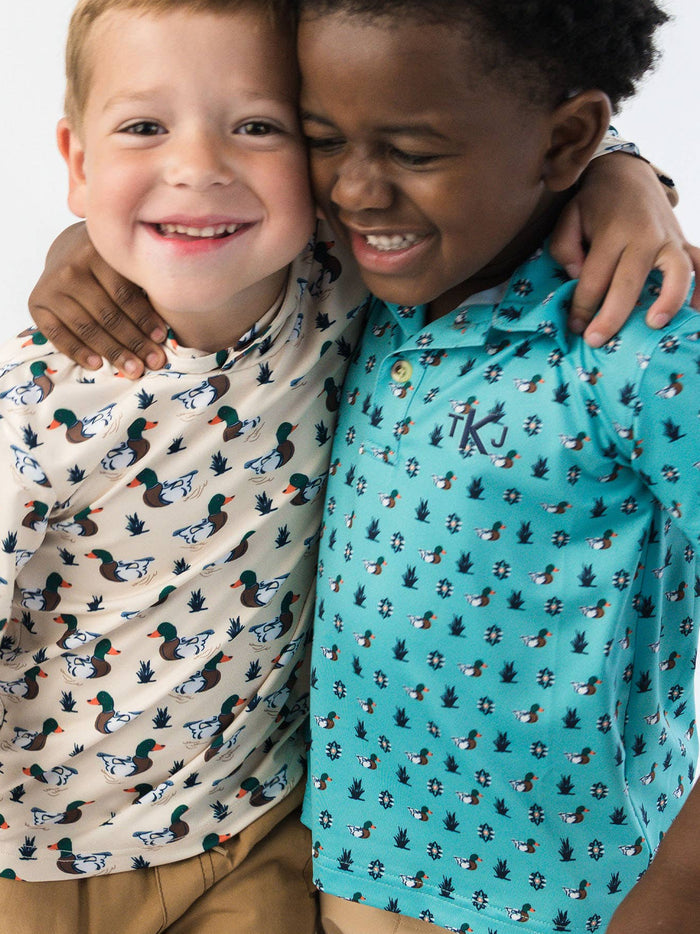 Two children wearing patterned shirts standing close together on a white background