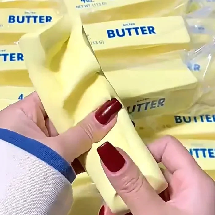 Hands holding a stick of butter with multiple butter packages in the background.