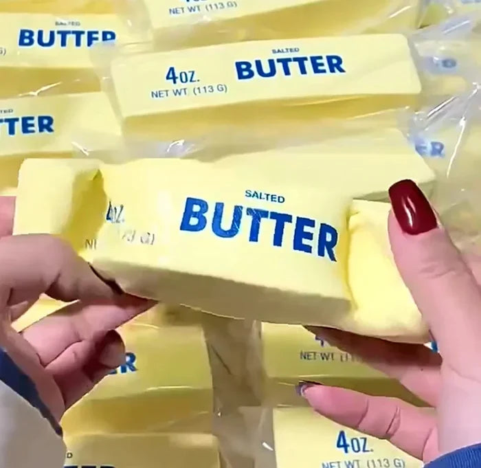 Hands holding a package of salted butter with multiple butter packages in the background.