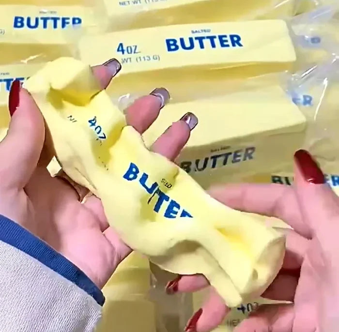 Hand holding a stick of butter with 'BUTTER' branding, surrounded by more butter packages.