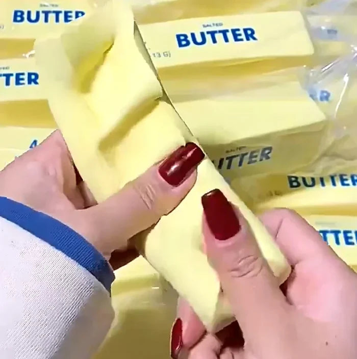 Hands holding a block of butter with 'BUTTER' labeled on it, surrounded by more butter blocks.