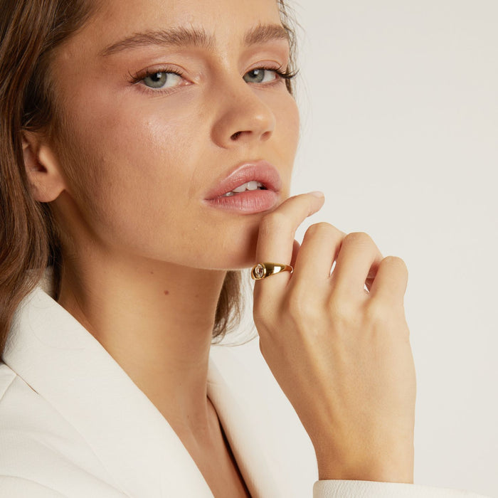 Model. Close-up of a woman wearing a gold ring on a plain background