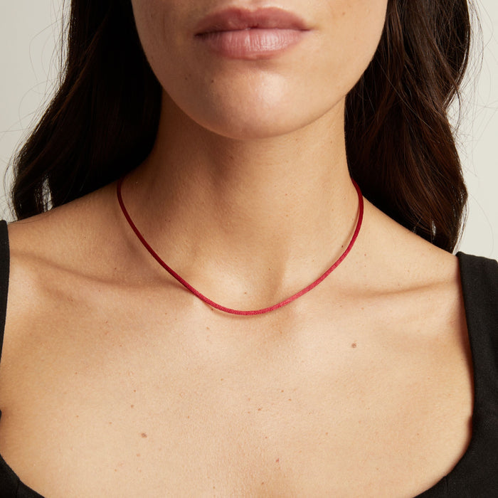 Model. A close-up of a model wearing a thin cord necklace, showing the necklace against her neck and upper chest.