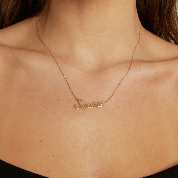 Model Close-up of a woman wearing a delicate gold chain necklace with a script nameplate pendant that reads "Sophie".
