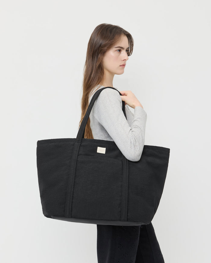 Dina Black Travel Tote in black nylon, Lolo Pointelle Long-Sleeve Top in grey cotton, and Demi Embroidered Pant in black denim.