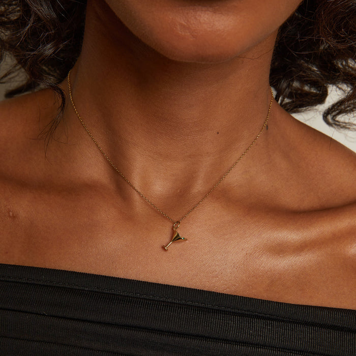 Model. Close-up of a person wearing a gold necklace with a small pendant.