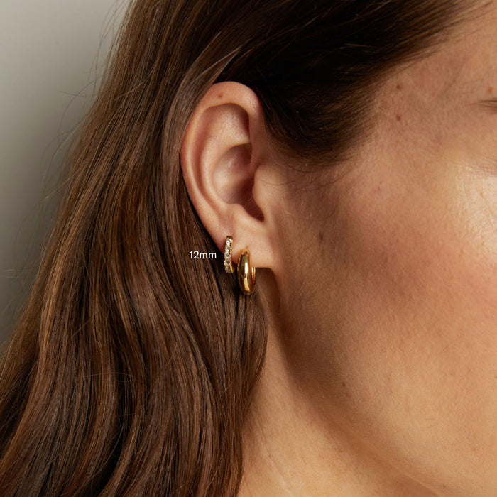 Model. Close-up of an ear wearing a gold hoop earring with '12mm' label.