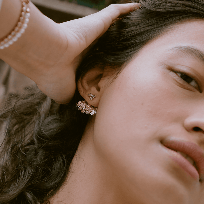 Lifestyle Model. A close-up lifestyle shot of a woman wearing statement gold stud earrings outdoors