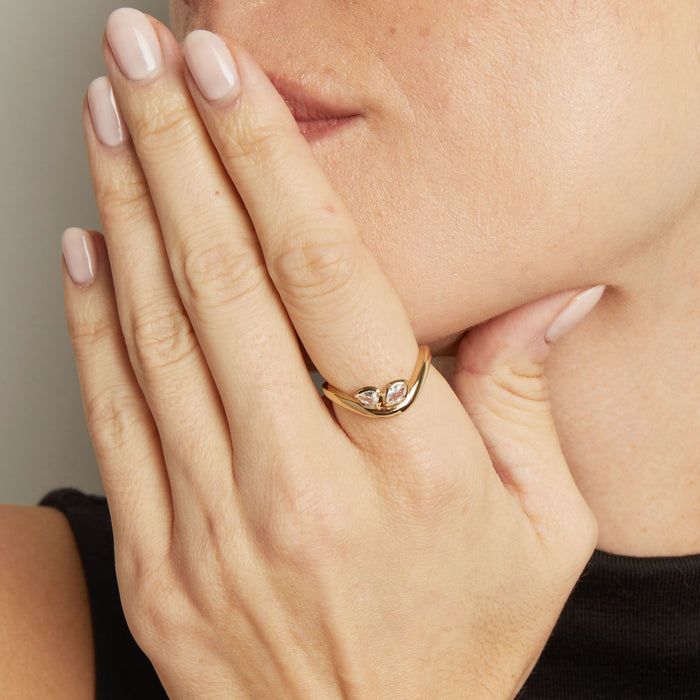 Model. Close-up of a hand wearing a gold ring with a diamond, holding the face.