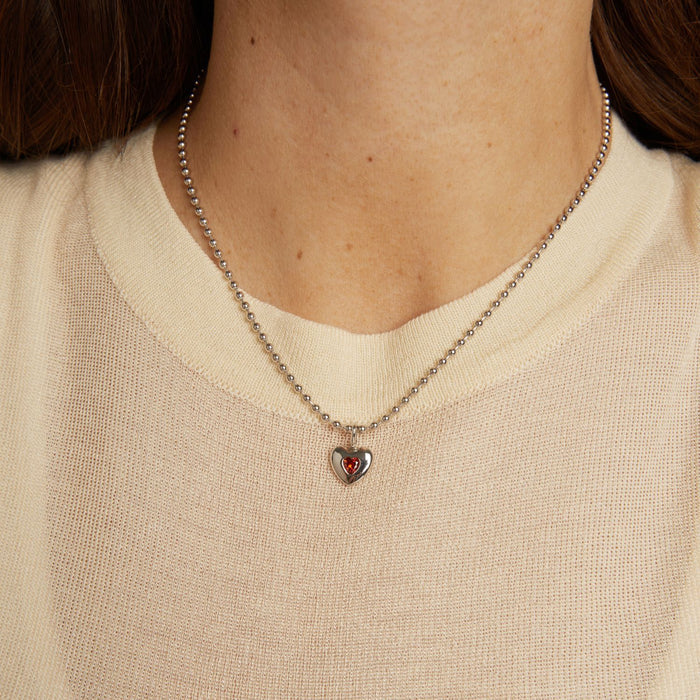 Model. Necklace with a heart-shaped pendant worn by a person