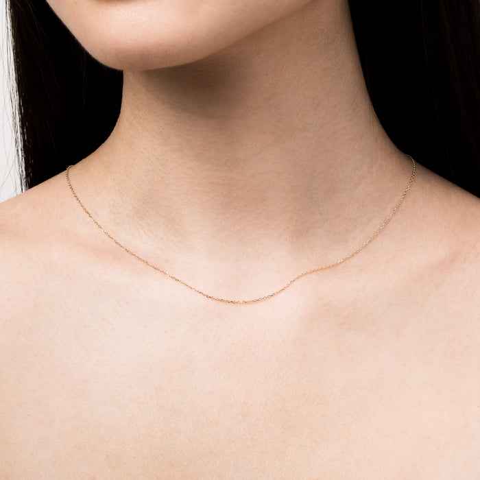 Model Close-up of a woman wearing a single delicate gold chain necklace.