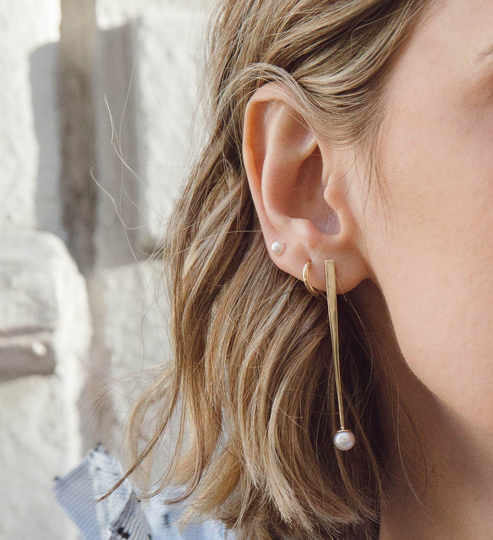 Gold Huggies Lifestyle Model. A close-up lifestyle shot of a woman wearing various earrings.