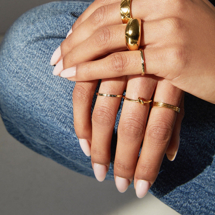 Lifestyle Model. Close up of hand wearing various gold rings.