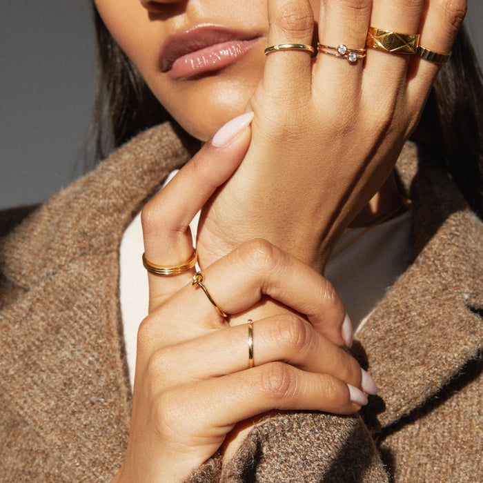 Model. Close up of woman's hands wearing various gold rings.