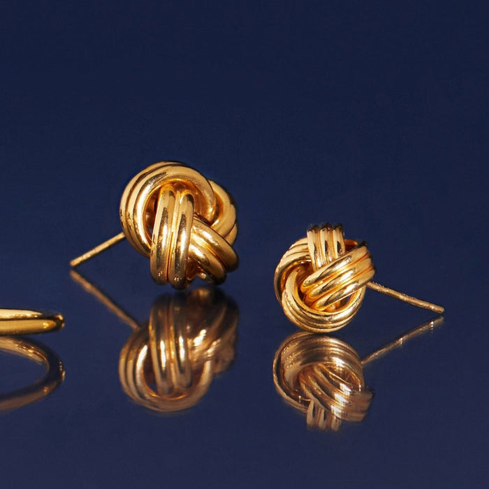 Flatlay Model gold knotted earrings on a blue background