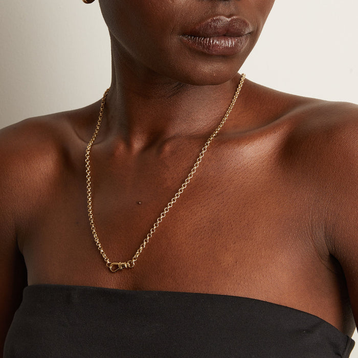 Model Close-up of a woman wearing a gold chain necklace with a ring clasp.
