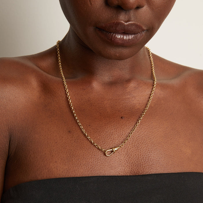 Model Close-up of a woman wearing a gold chain necklace with a ring clasp.