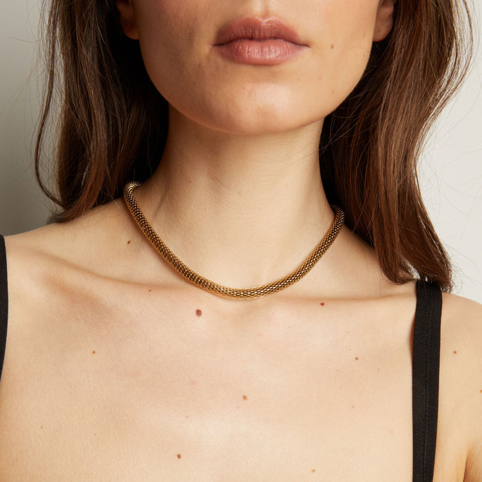Gold chain necklace on woman in black tank top. Model
