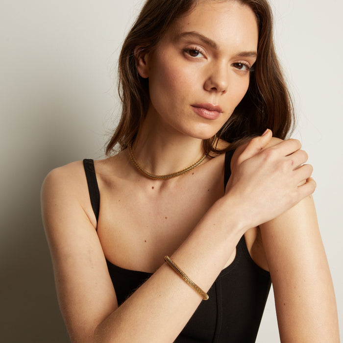 Gold chain bracelet and necklace on woman in black tank top. Model