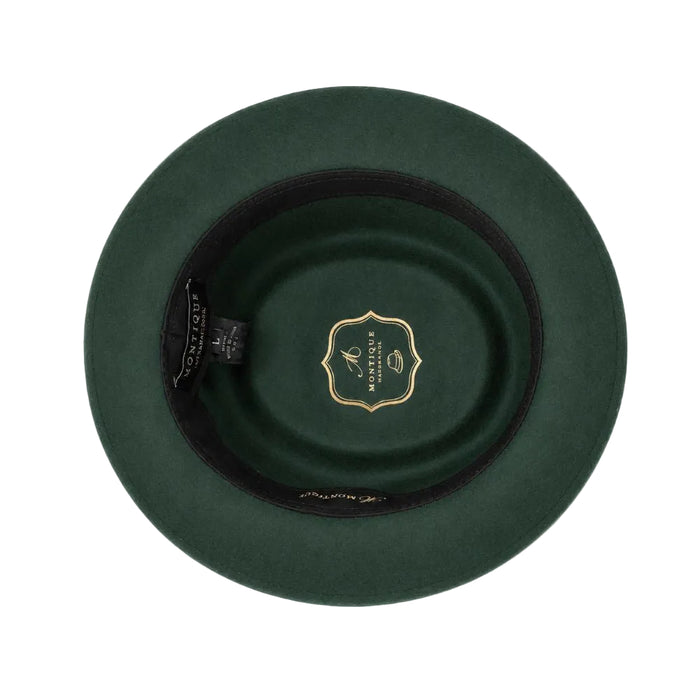 Top-down view of a dark green felt hat with a black inner band and a gold shield-shaped logo in the center