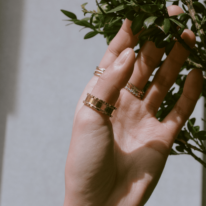Lifestyle Model. Close up of woman's hand grabbing a tree wearing various rings