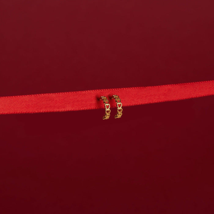 Flatlay Model. Close up of gold heart hoop earrings on red background
